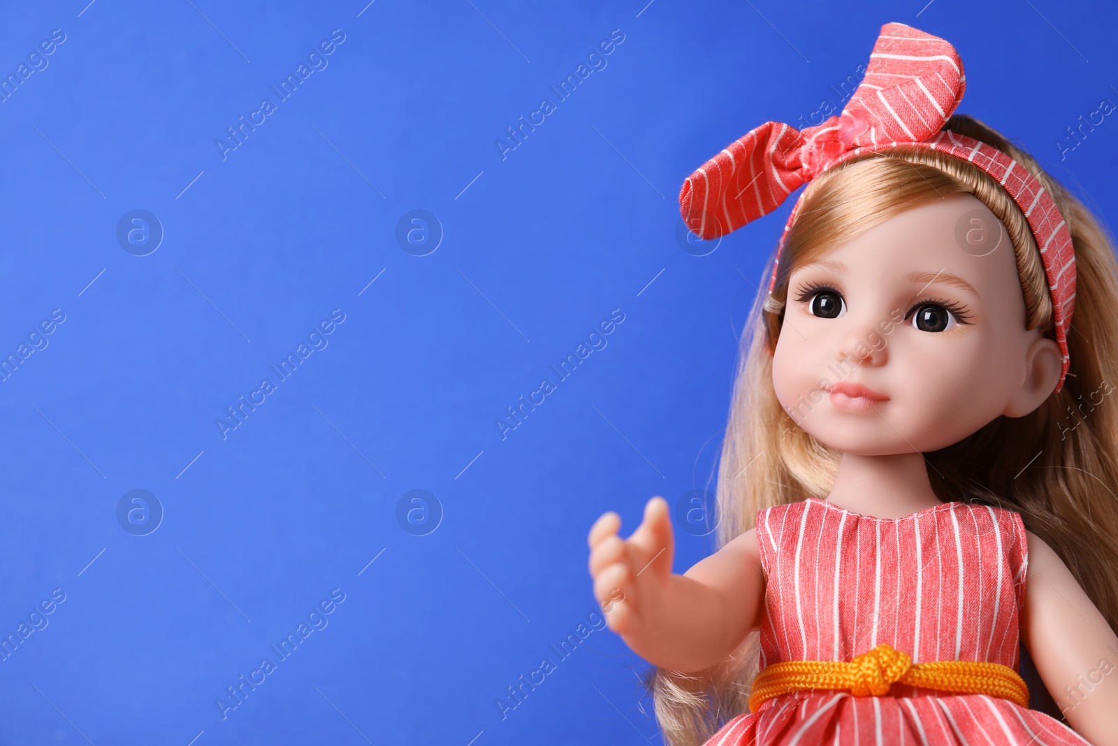 Photo of Beautiful doll in dress and headband on blue background, closeup. Space for text