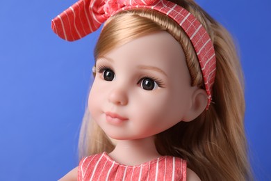 Photo of Beautiful doll in headband on blue background, closeup