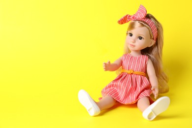 Photo of Beautiful doll in dress and headband on yellow background. Space for text