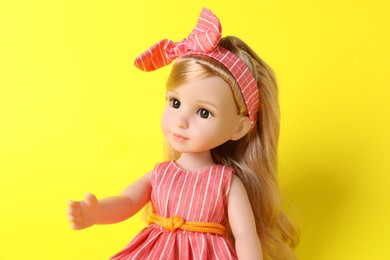 Beautiful doll with headband on yellow background, closeup