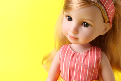 Beautiful doll on yellow background, closeup. Space for text