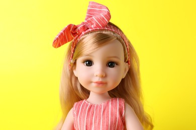 Photo of Beautiful doll with headband on yellow background, closeup