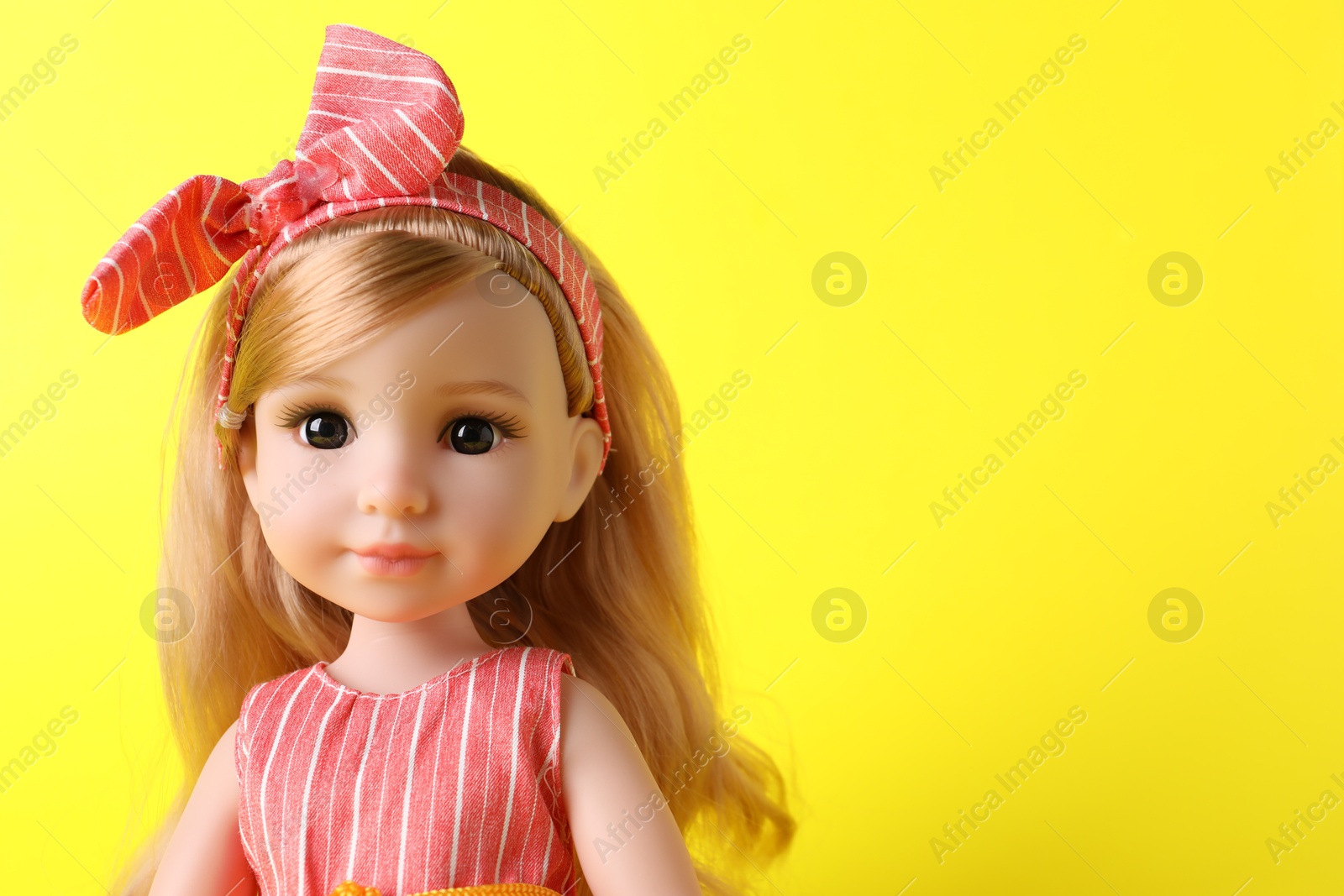 Photo of Beautiful doll with headband on yellow background, closeup. Space for text