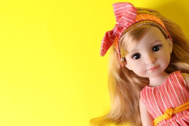 Photo of Beautiful doll in headband on yellow background, closeup. Space for text