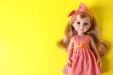 Photo of Beautiful doll in dress and headband on yellow background, top view. Space for text