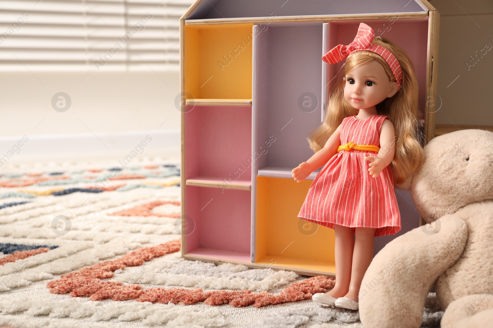 Photo of Beautiful doll, teddy bear and dollhouse on soft carpet indoors