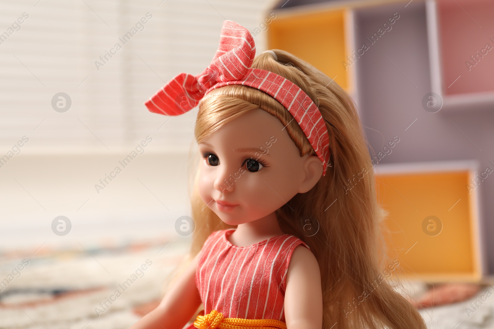 Photo of Beautiful doll in dress and headband indoors, closeup