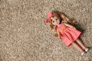 Photo of Beautiful doll in dress and headband on soft carpet, top view. Space for text