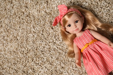 Photo of Beautiful doll in dress and headband on soft carpet, top view. Space for text