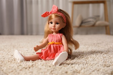 Photo of Beautiful doll in dress and headband on soft carpet