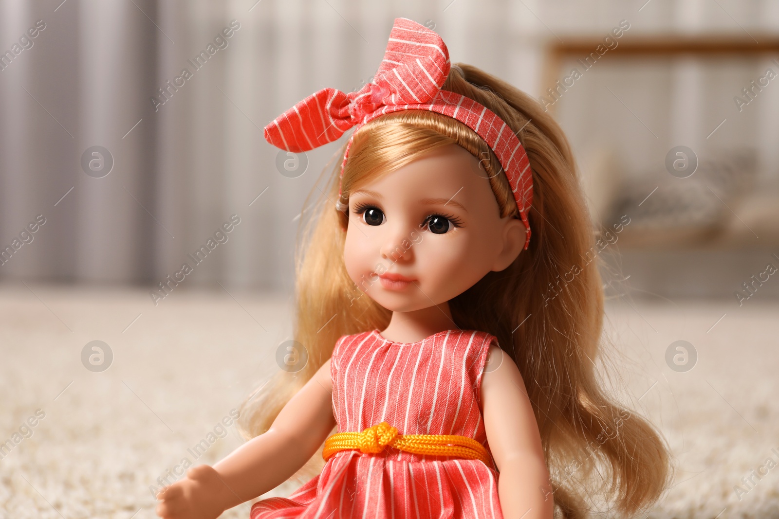 Photo of Beautiful doll in dress and headband indoors, closeup