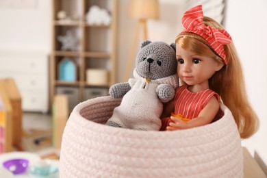 Photo of Beautiful doll and toy bear in basket indoors, closeup