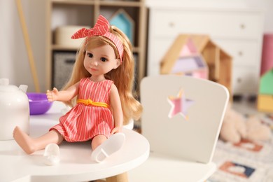 Photo of Beautiful doll and toy dishware on white table indoors. Space for text