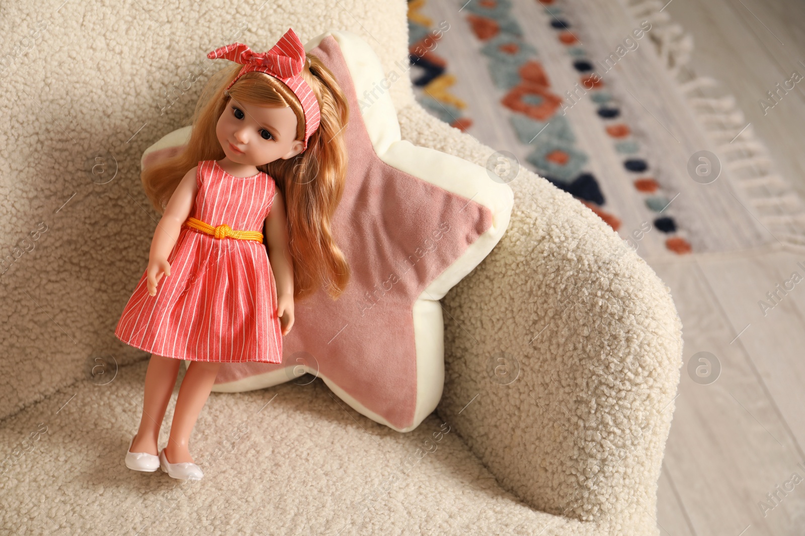 Photo of Beautiful doll and star shaped pillow in armchair indoors