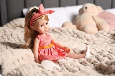 Photo of Beautiful doll in dress and headband on bed