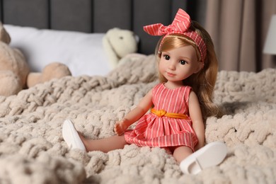 Photo of Beautiful doll in dress and headband on bed