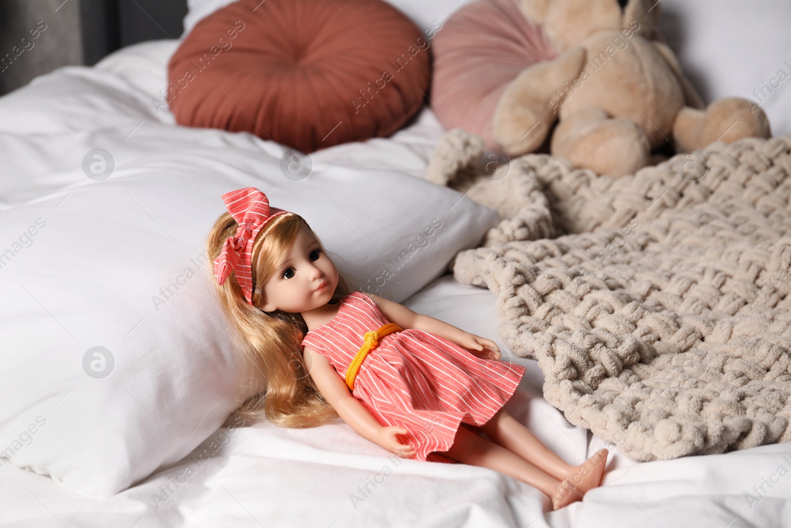 Photo of Beautiful doll in dress and headband on bed