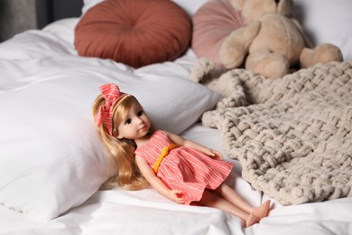 Photo of Beautiful doll in dress and headband on bed