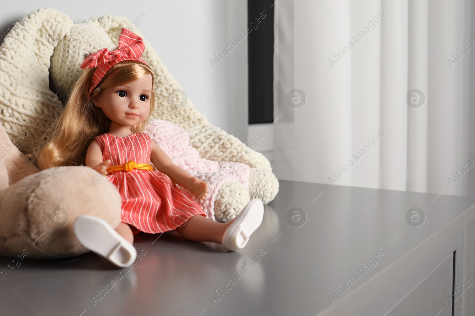 Photo of Beautiful doll and toy bunny on grey table indoors. Space for text