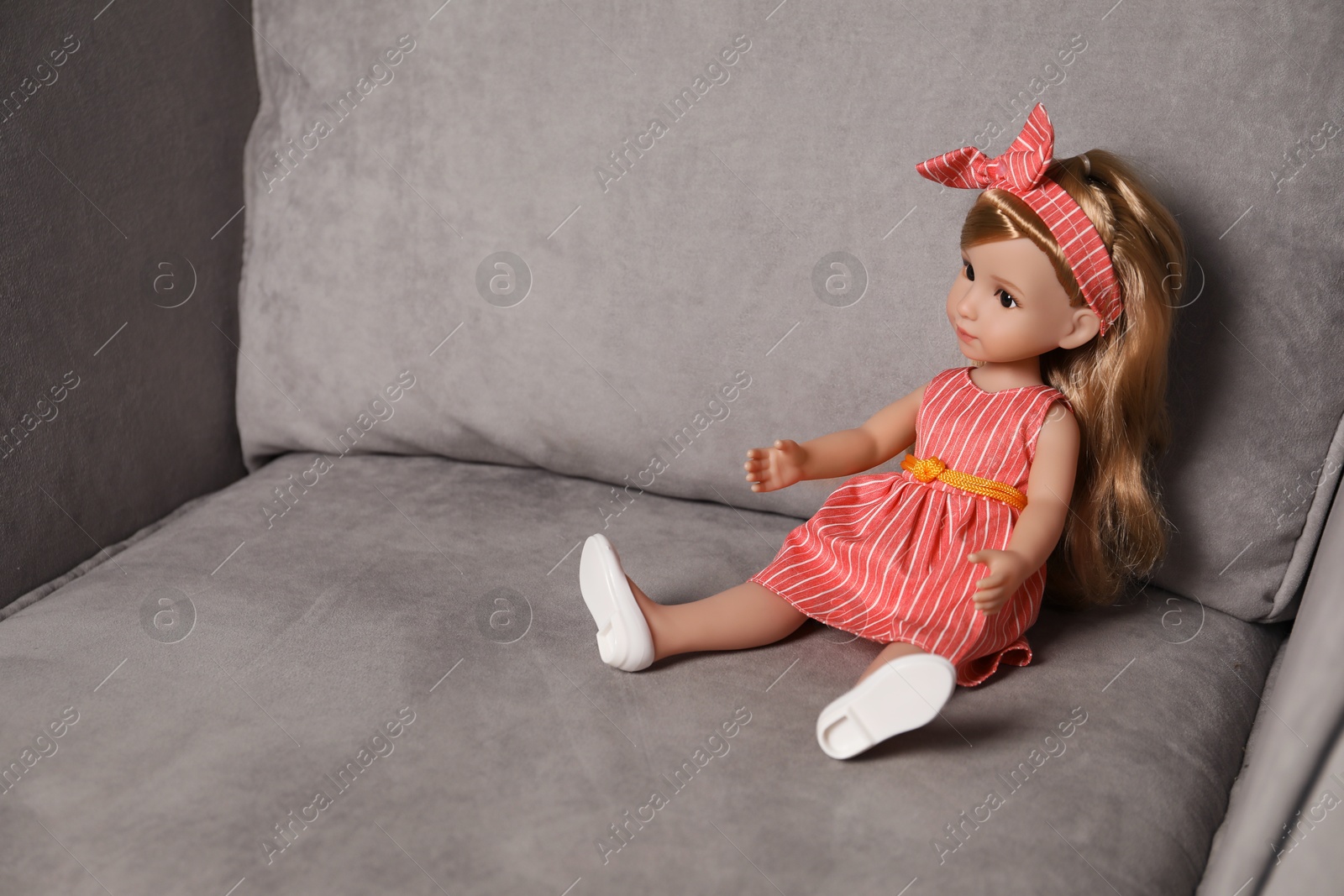 Photo of Beautiful doll with headband in armchair. Child's toy