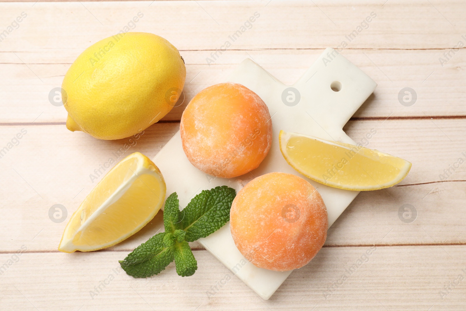 Photo of Delicious mochi, lemons and mint on wooden table, flat lay