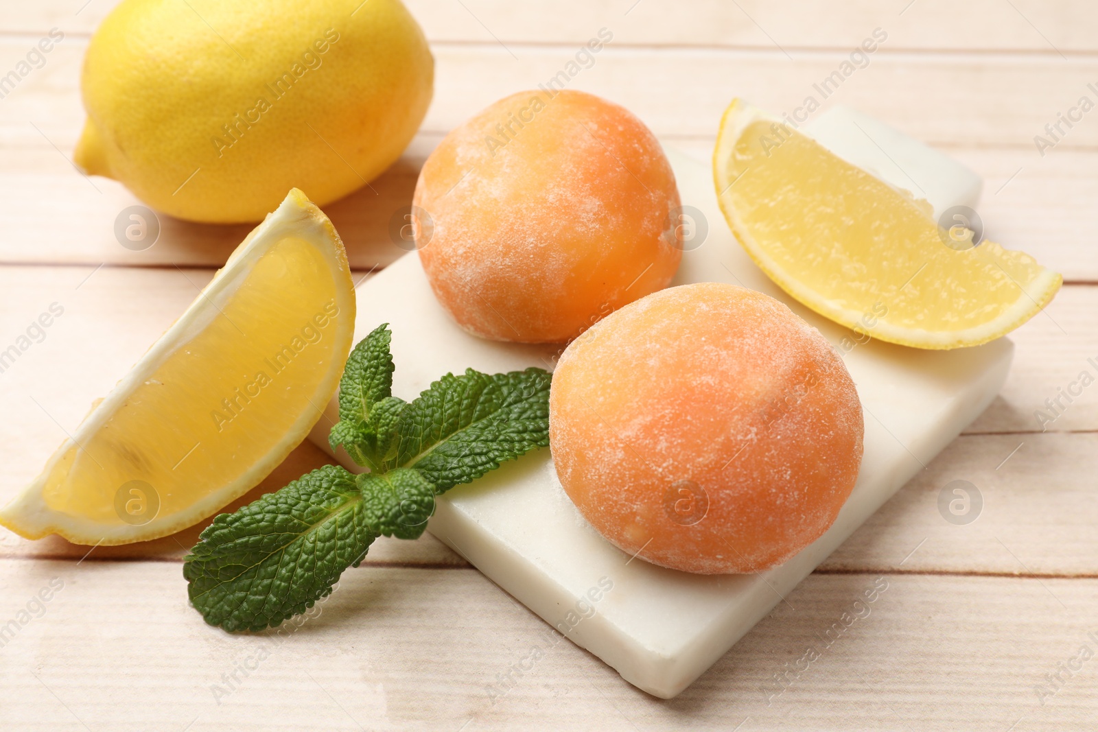 Photo of Delicious mochi, lemons and mint on wooden table, closeup