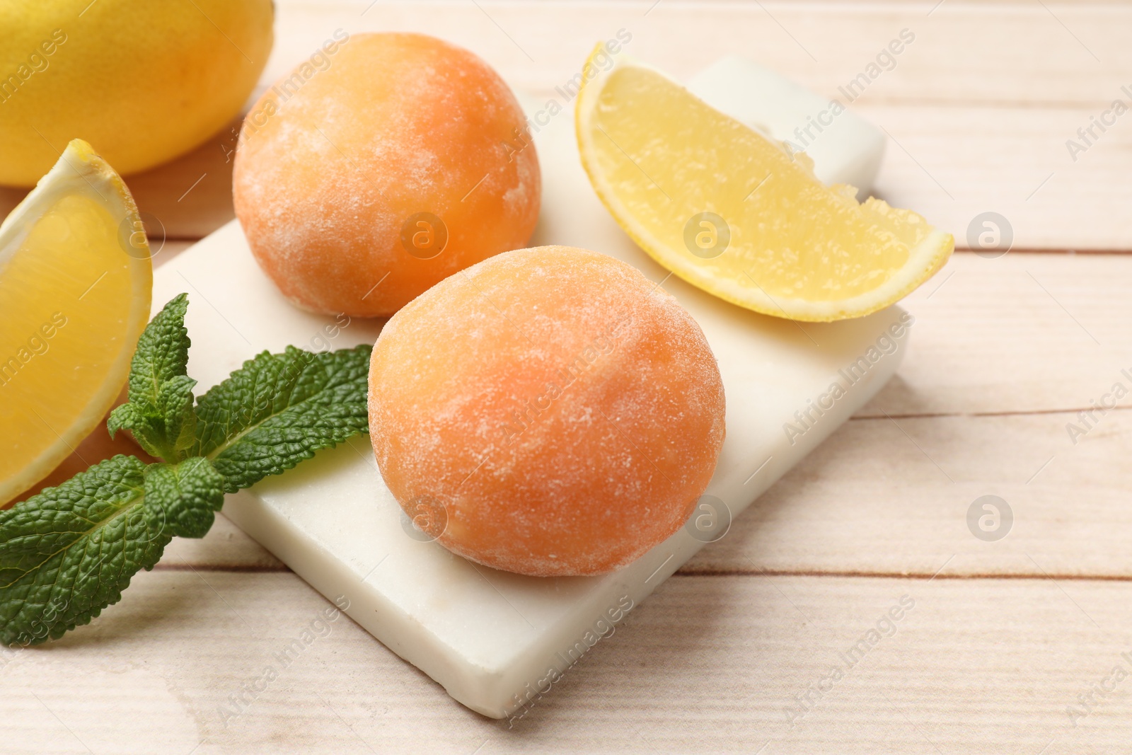 Photo of Delicious mochi, lemons and mint on wooden table, closeup