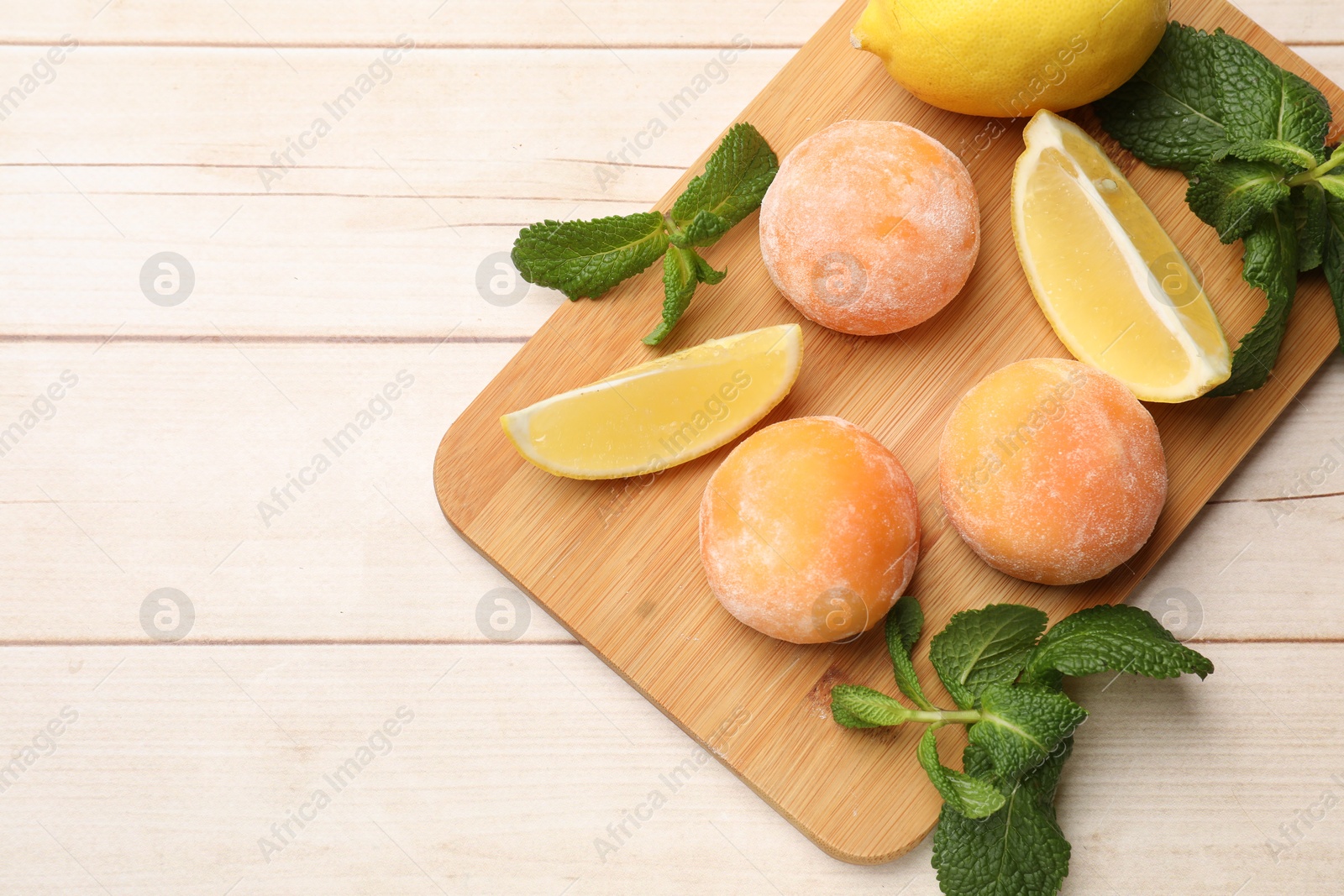 Photo of Delicious mochi, lemons and mint on wooden table, top view. Space for text