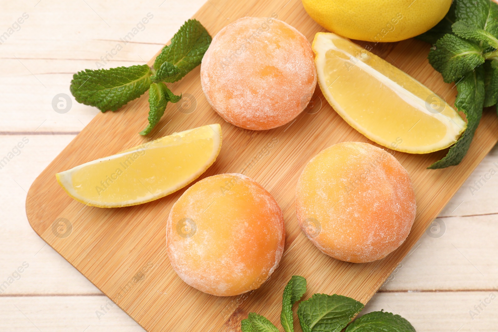 Photo of Delicious mochi, lemons and mint on wooden table, top view.