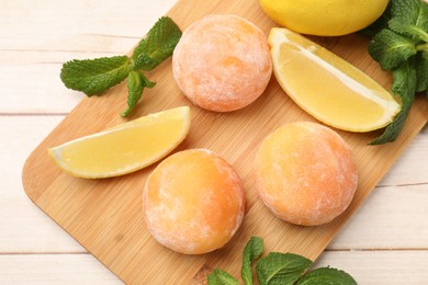 Photo of Delicious mochi, lemons and mint on wooden table, top view.