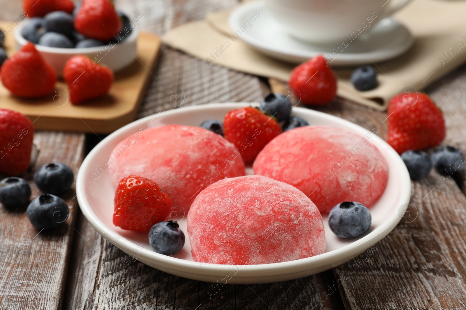 Photo of Delicious mochi, strawberries and blueberries on wooden table, closeup