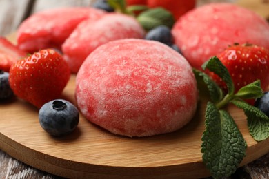 Photo of Delicious mochi, strawberries, blueberries and mint on wooden table, closeup