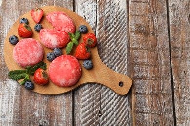 Photo of Delicious mochi, strawberries, blueberries and mint on wooden table, top view. Space for text