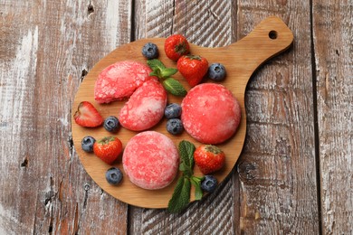 Photo of Delicious mochi, strawberries, blueberries and mint on wooden table, top view