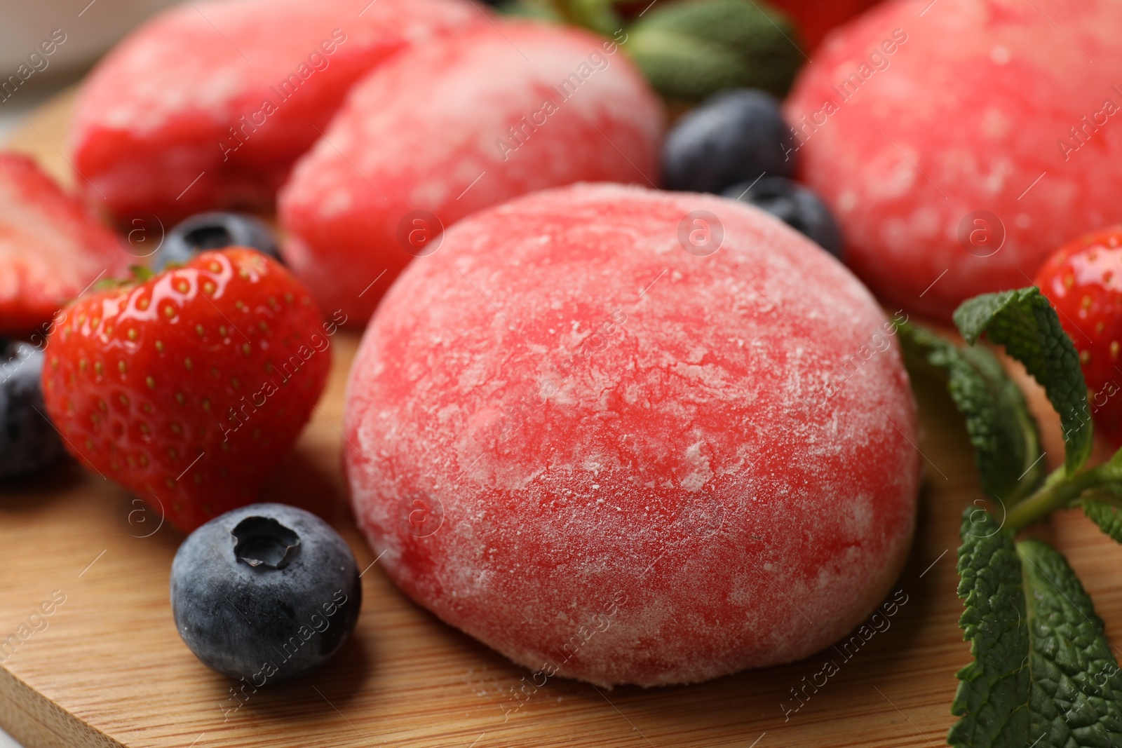 Photo of Delicious mochi, strawberries, blueberries and mint on wooden table, closeup