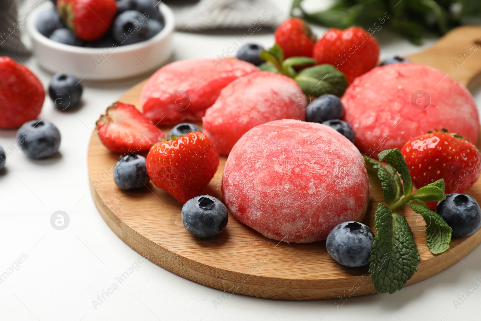 Photo of Delicious mochi, strawberries, blueberries and mint on white table, closeup