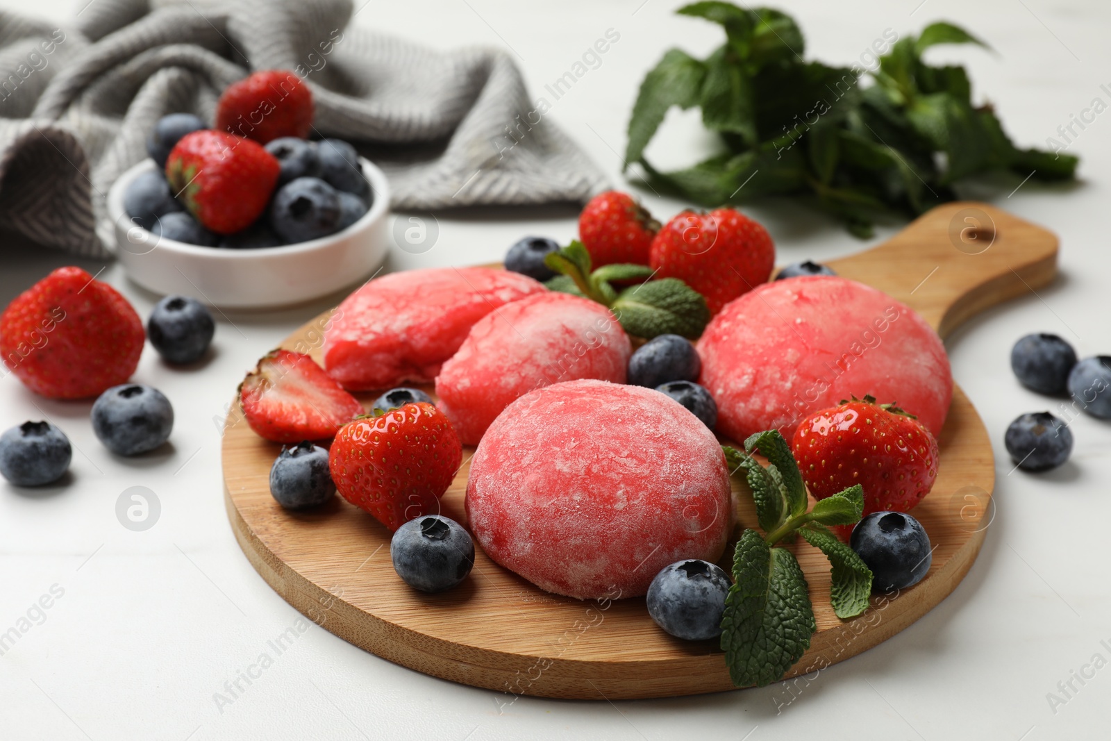 Photo of Delicious mochi, strawberries, blueberries and mint on white table, closeup