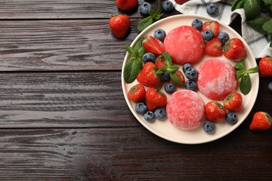 Photo of Delicious mochi, strawberries, blueberries and mint on wooden table, flat lay. Space for text