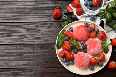 Photo of Delicious mochi, strawberries, blueberries and mint on wooden table, flat lay. Space for text