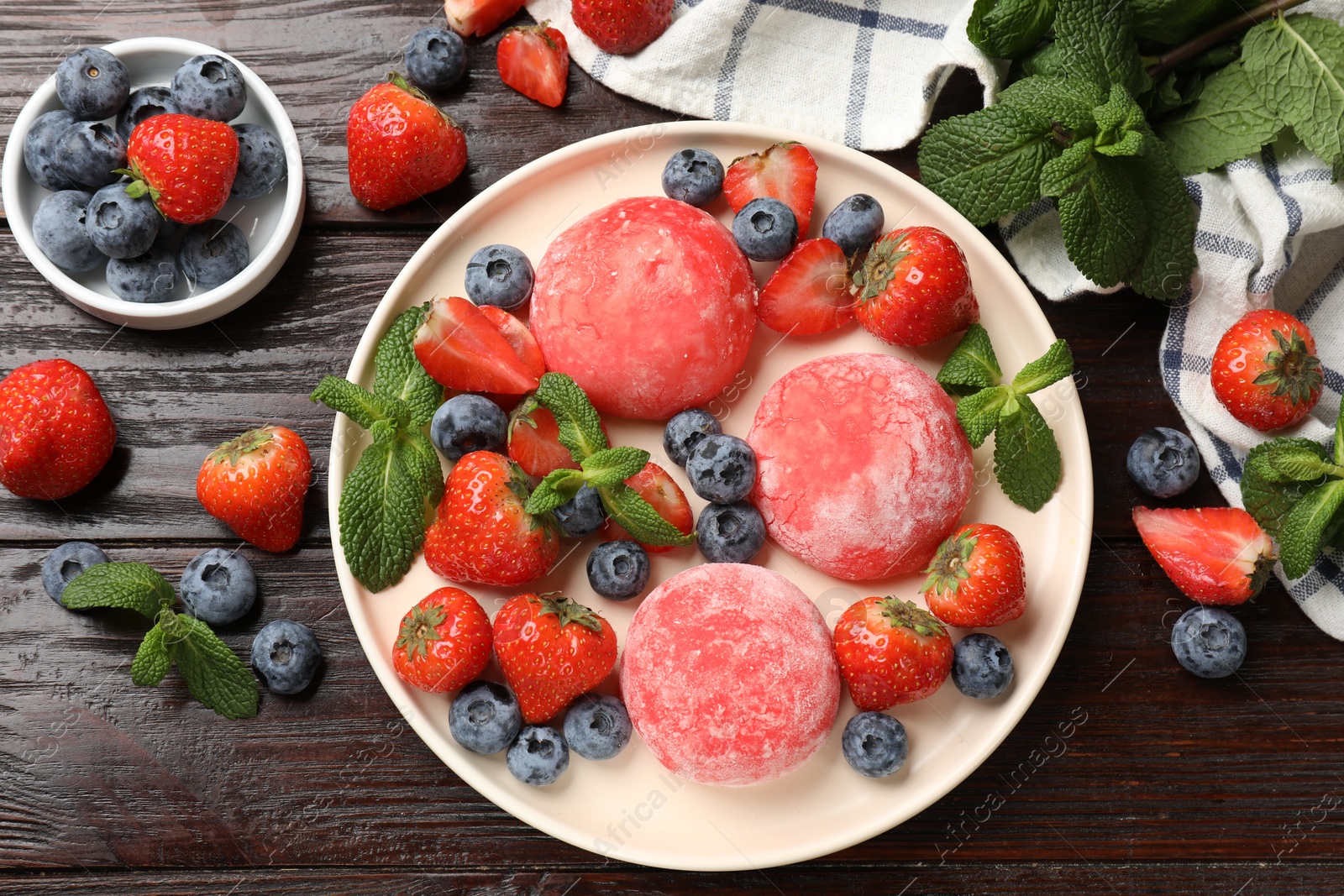 Photo of Delicious mochi, strawberries, blueberries and mint on wooden table, flat lay