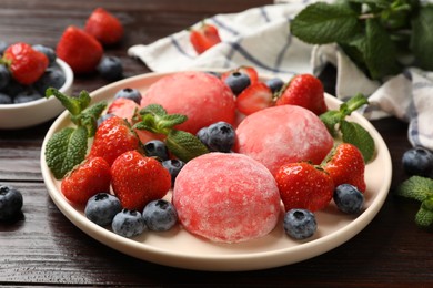 Photo of Delicious mochi, strawberries, blueberries and mint on wooden table, closeup