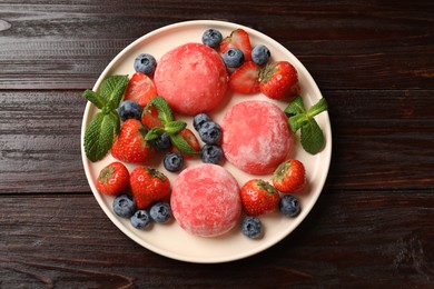 Photo of Delicious mochi, strawberries, blueberries and mint on wooden table, top view