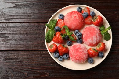 Photo of Delicious mochi, strawberries, blueberries and mint on wooden table, top view. Space for text