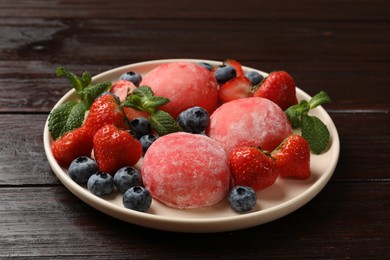 Photo of Delicious mochi, strawberries, blueberries and mint on wooden table, closeup