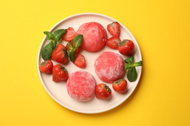 Photo of Delicious mochi, strawberries and mint on yellow table, top view