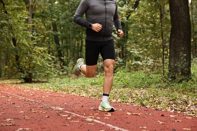 Photo of Athletic man running in park, closeup. Healthy lifestyle