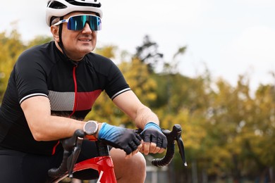 Photo of Athletic man with helmet and bicycle outdoors, space for text