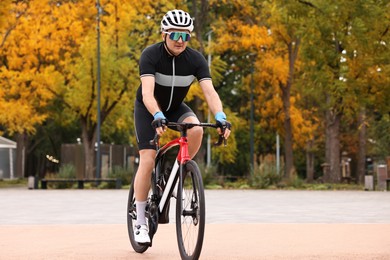 Photo of Athletic man with helmet riding bicycle outdoors