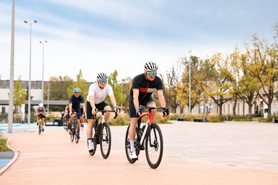 Photo of Group of athletic people riding bicycles outdoors, space for text