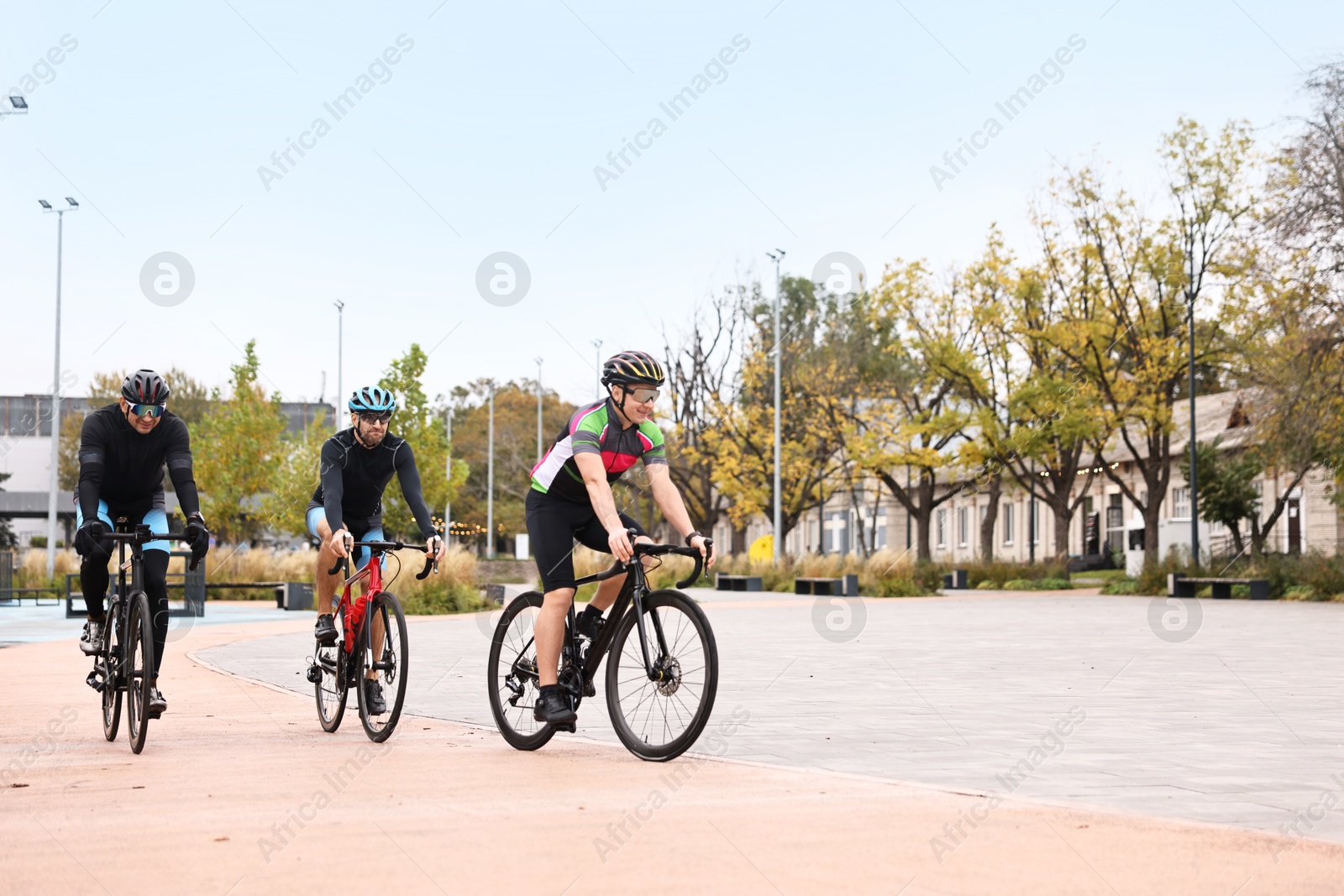 Photo of Group of athletic people riding bicycles outdoors, space for text